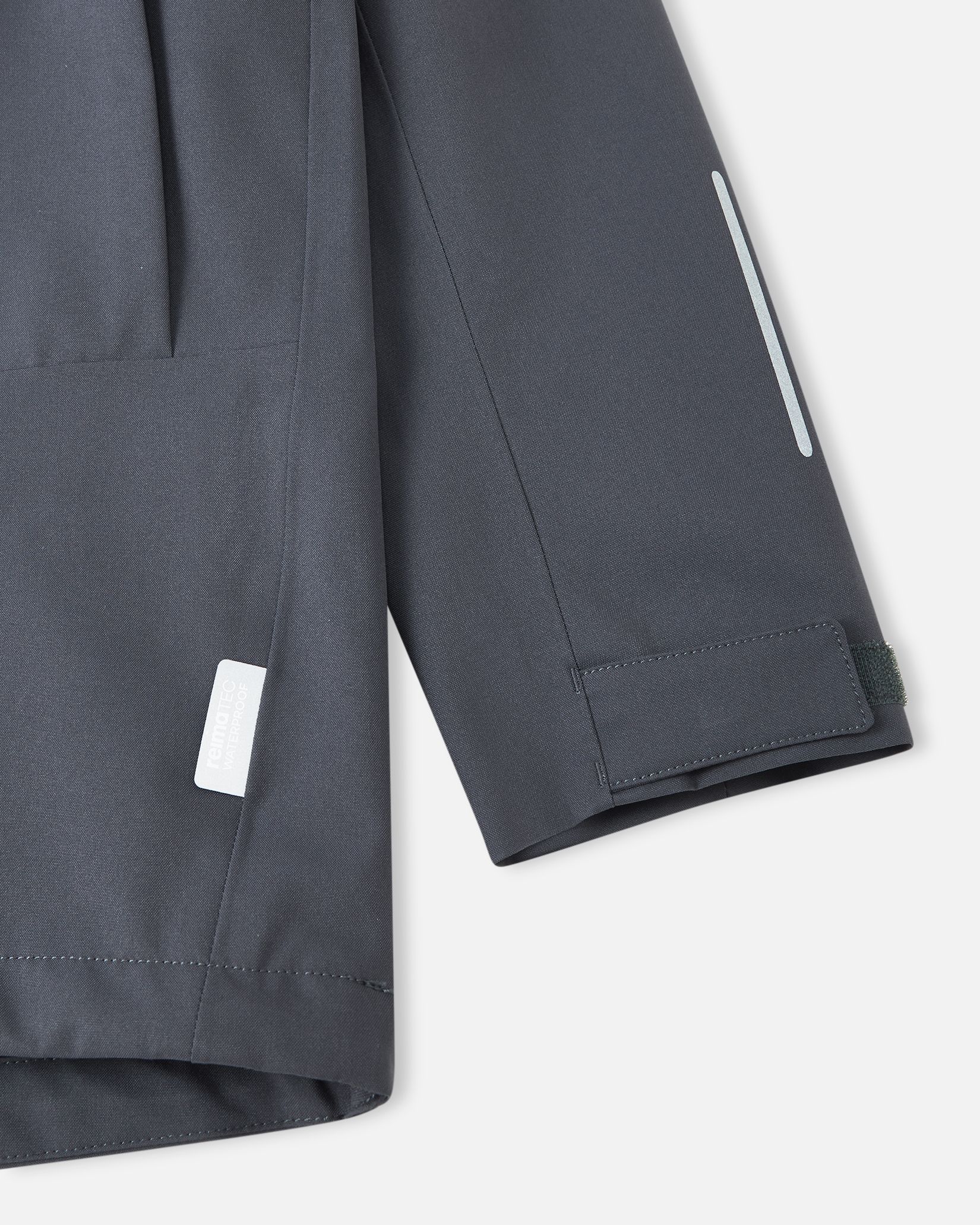 Close-up of the adjustable velcro sleeve cuff and safety reflective detailing on the soft black Reima Saarela kids waterproof jacket.