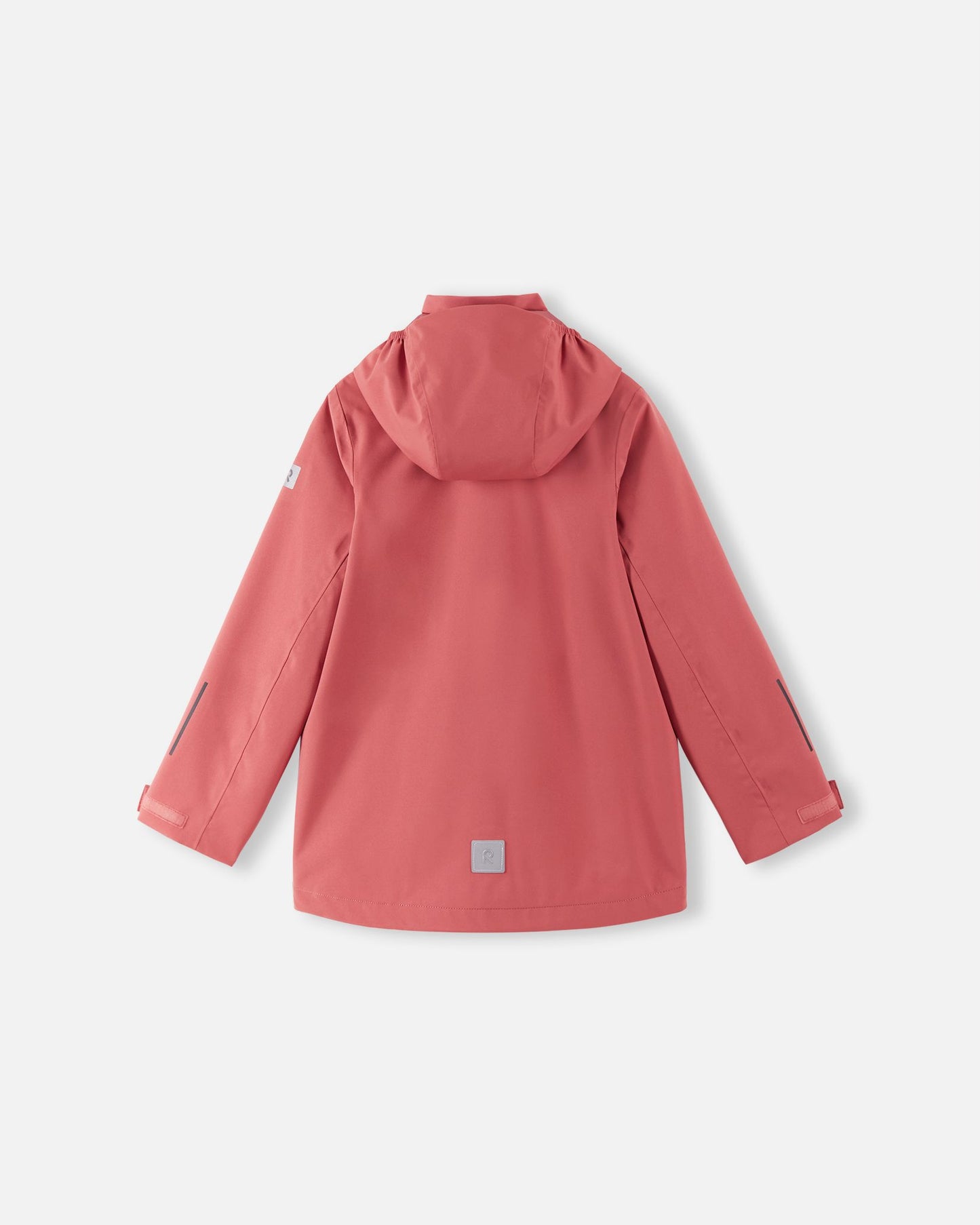 Back view of the red clay Reima Saarela kids' waterproof shell jacket, showing the attached hood, dropped back hem for extra coverage, and a highly visible reflective safety patch near the hemline.