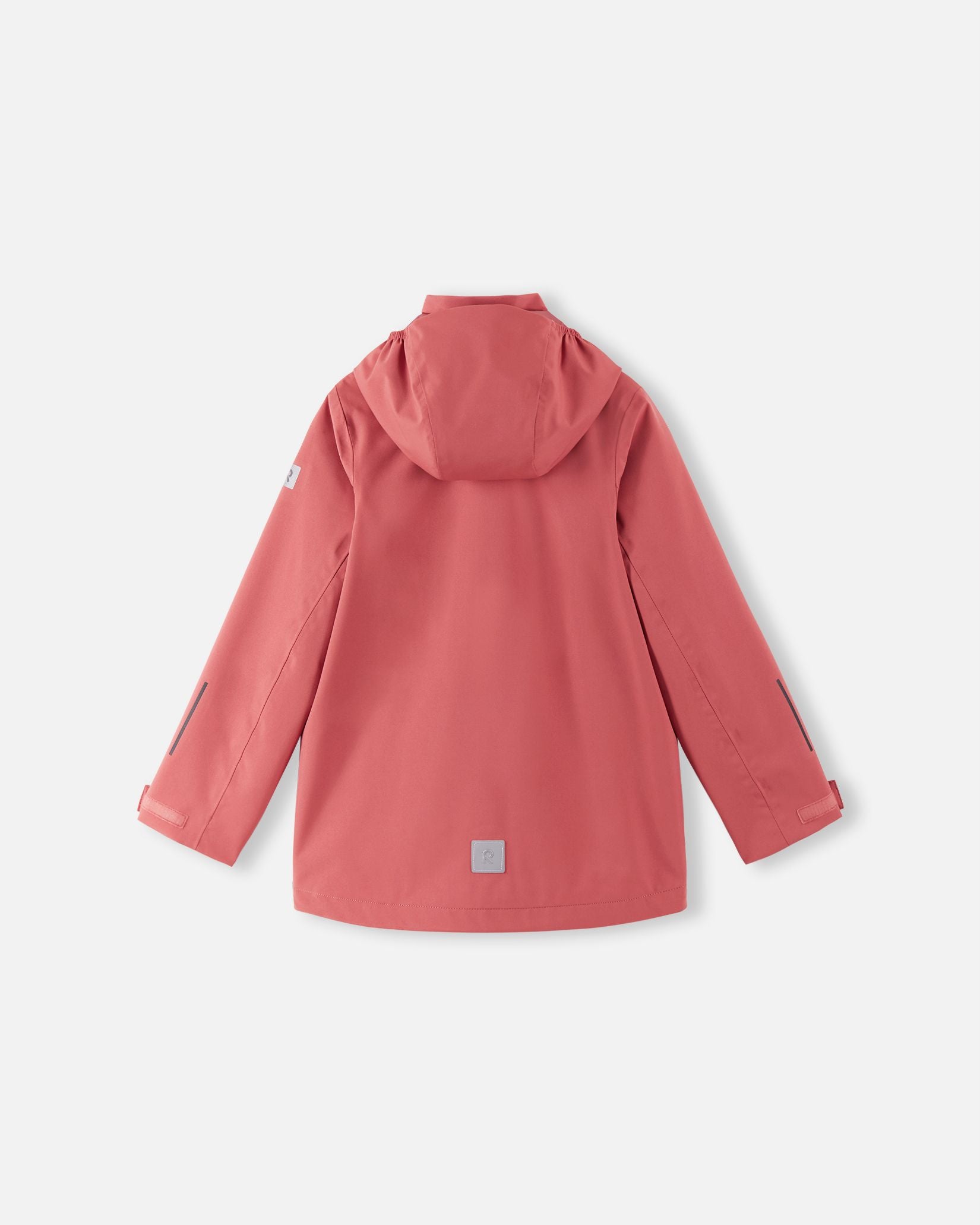 Back view of the red clay Reima Saarela kids' waterproof shell jacket, showing the attached hood, dropped back hem for extra coverage, and a highly visible reflective safety patch near the hemline.