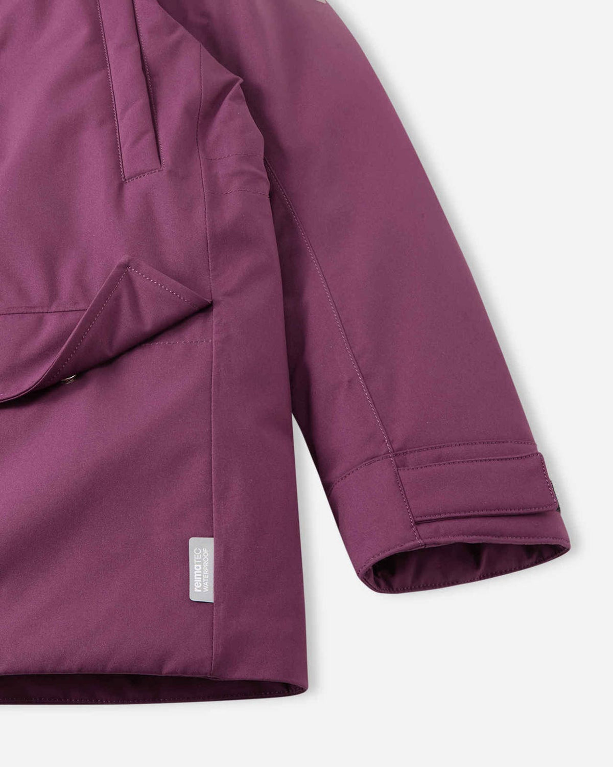 Close-up of the sleeve cuff with adjustable Velcro strap and the lower pocket on the deep purple Reima Serkkula parka, featuring the sewn Reimatec waterproof label.