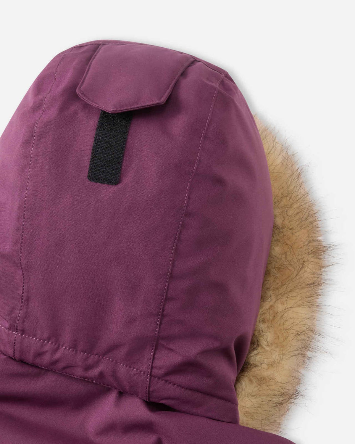 Detailed shot of the top crown of the deep purple Reima Serkkula parka hood, showing the Velcro adjustment tab designed to tailor hood depth and preserve peripheral vision.
