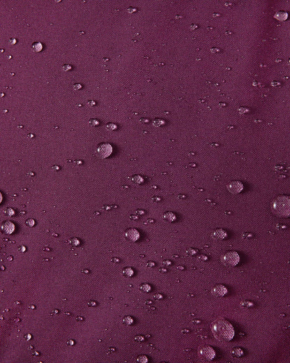 A macro close-up of the deep purple Reimatec fabric used on the Reima Serkkula kids' down parka, showing multiple water droplets beading on the surface to demonstrate its fully waterproof and water-repellent capabilities.