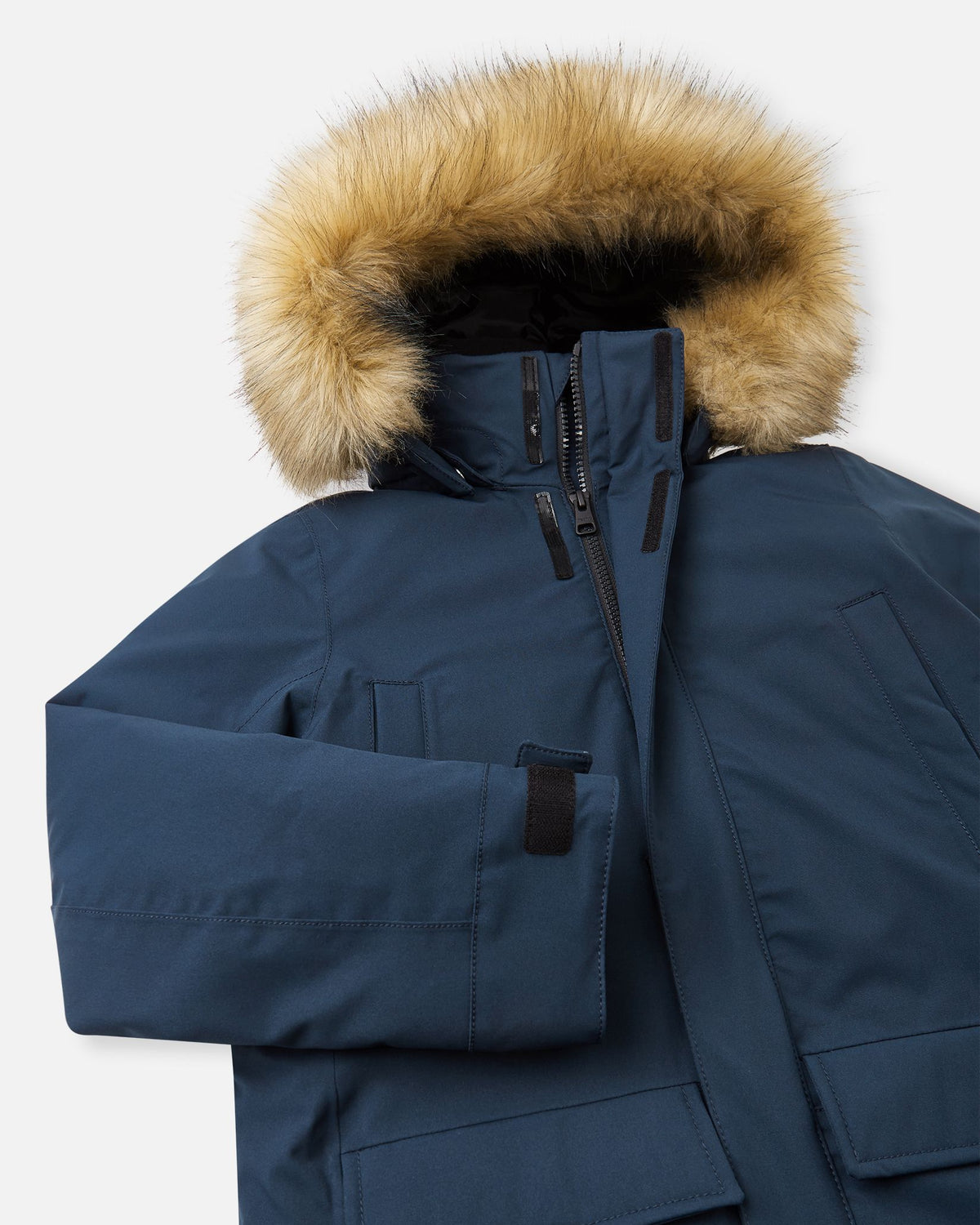 Close-up of the upper chest and collar on the navy Reima Serkkula kids' parka, displaying the front zipper flap and faux-fur hood.