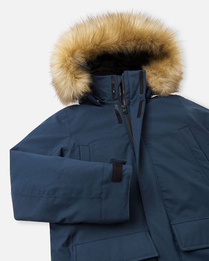 Close-up of the upper chest and collar on the navy Reima Serkkula kids' parka, displaying the front zipper flap and faux-fur hood.