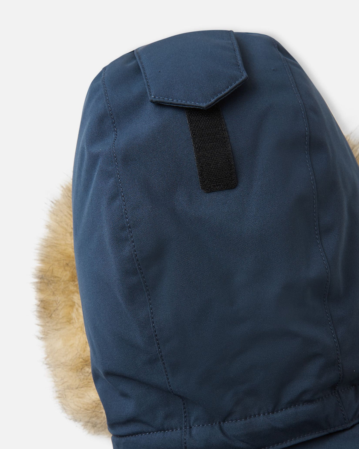Macro shot of the navy Reima Serkkula parka hood crown, highlighting the Velcro tab used for depth and fit adjustment.
