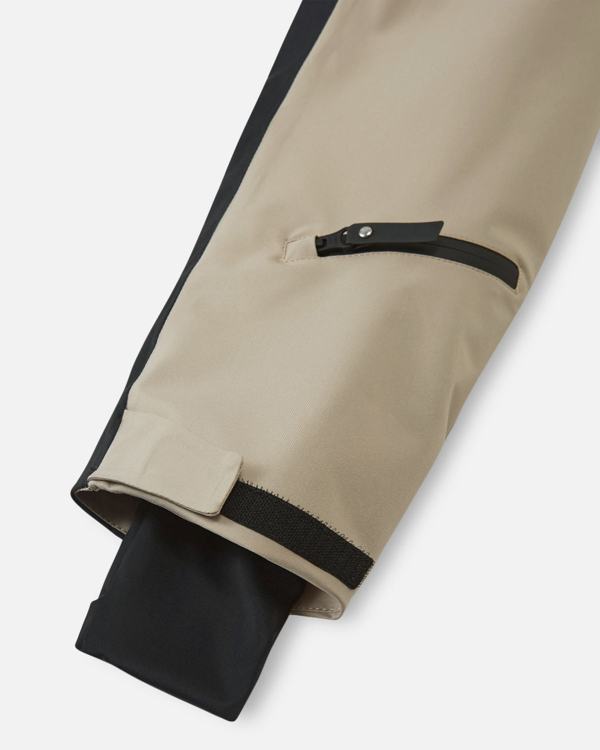 Close-up of the sleeve on the earthy beige Reima Skaulo kids ski suit, featuring adjustable cuffs with velcro straps and a comfortable inner lycra cuff.