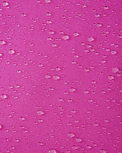Macro detail shot of water droplets beading up on the bright fuchsia fabric of the Reima Skaulo girls ski suit, demonstrating its high-quality waterproof and dirt-repellent finish.