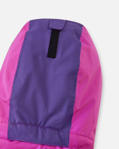 Close-up of the back of the hood on the fuchsia Reima Skaulo girls ski suit, showing the purple color-blocking detail and a velcro strap for easy depth adjustment.