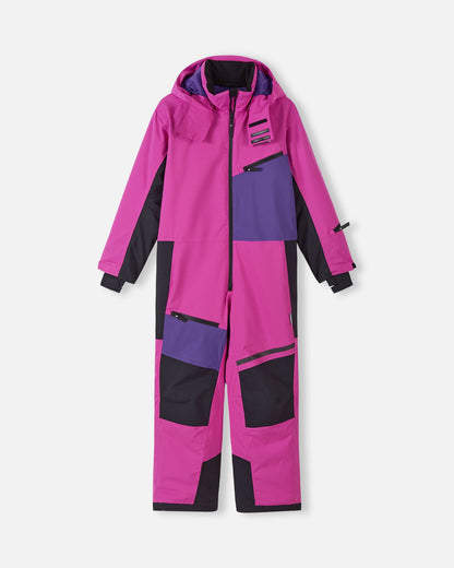 Front view of the Reima Skaulo girls ski suit in bright fuchsia, featuring purple and black color-blocked panels, a front zipper, and a secure zippered chest pocket.