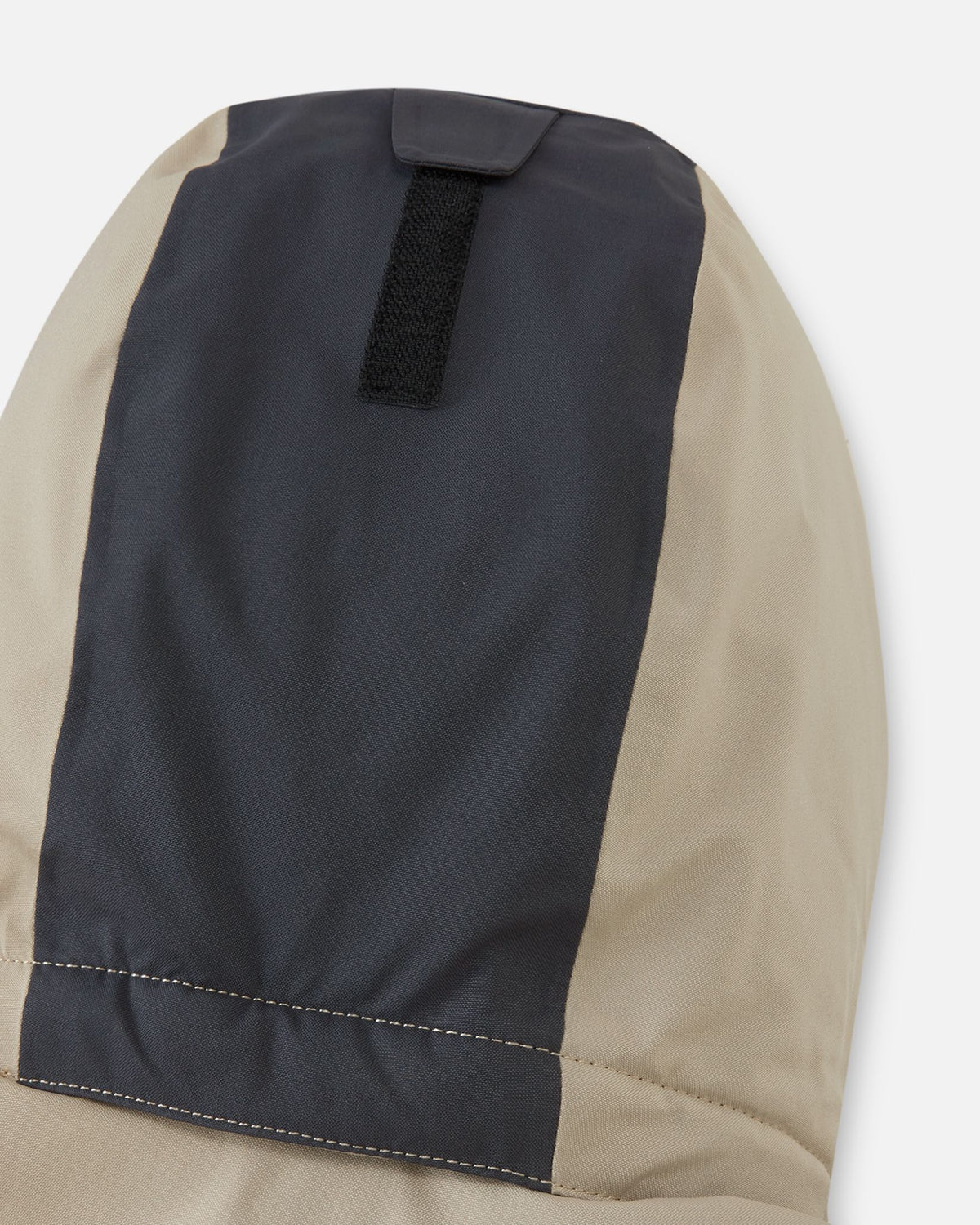 Close-up of the back of the lined, detachable hood on the Reima Skaulo kids ski suit in earthy beige, featuring a velcro adjustment strap for a secure fit.