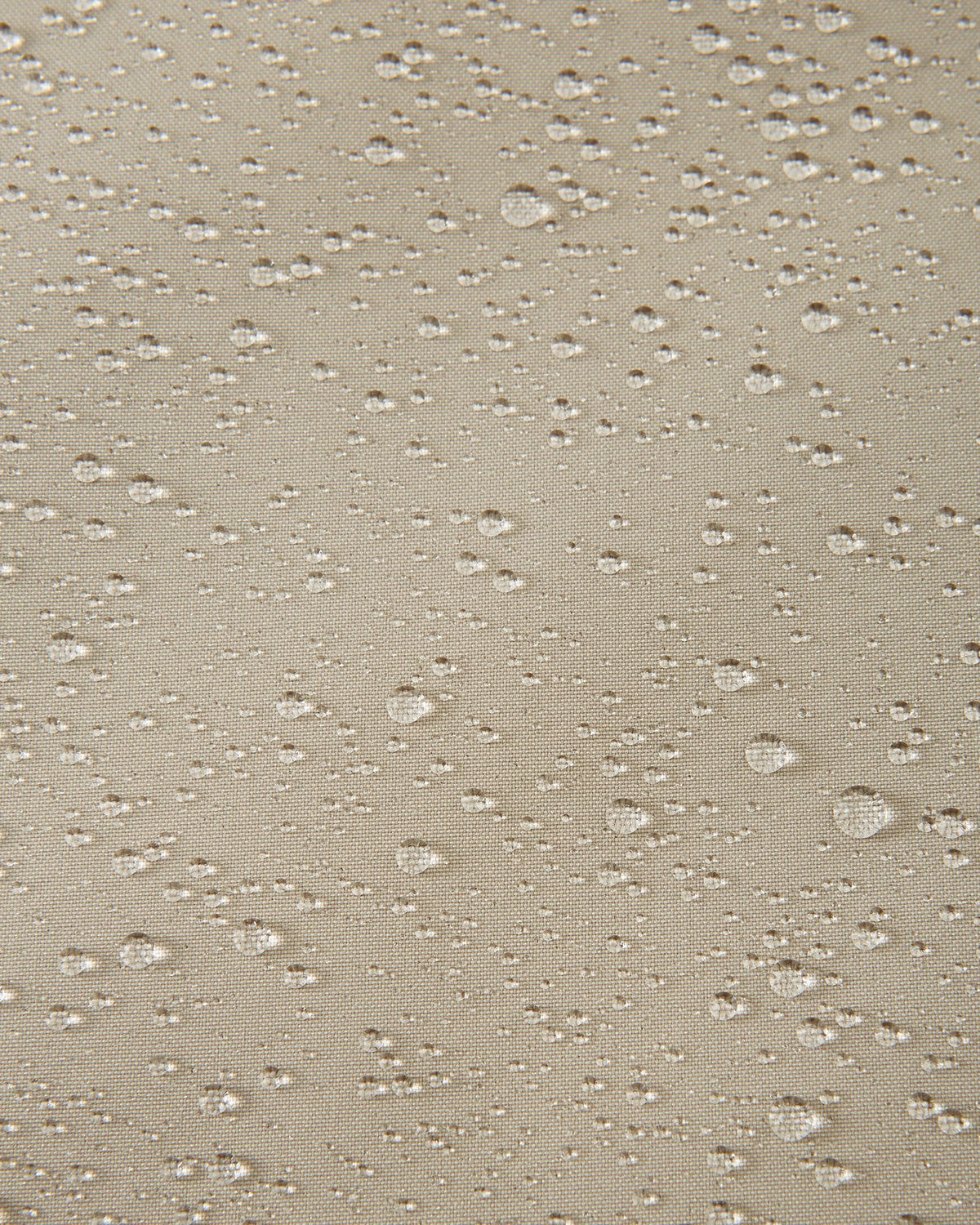 Macro shot of water droplets beading on the earthy beige fabric of the Reima Skaulo kids ski suit, demonstrating its high-quality waterproof and dirt-repellent material.