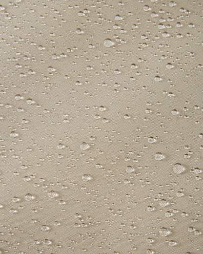 Macro shot of water droplets beading on the earthy beige fabric of the Reima Skaulo kids ski suit, demonstrating its high-quality waterproof and dirt-repellent material.