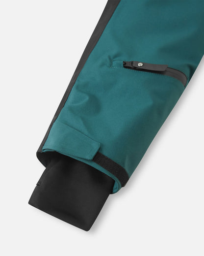 Close-up of the Reima Skaulo ski suit sleeve, featuring a convenient zippered ski pass pocket on the forearm, an adjustable velcro outer cuff, and a snug inner stretch cuff to lock in warmth and block wind and snow.