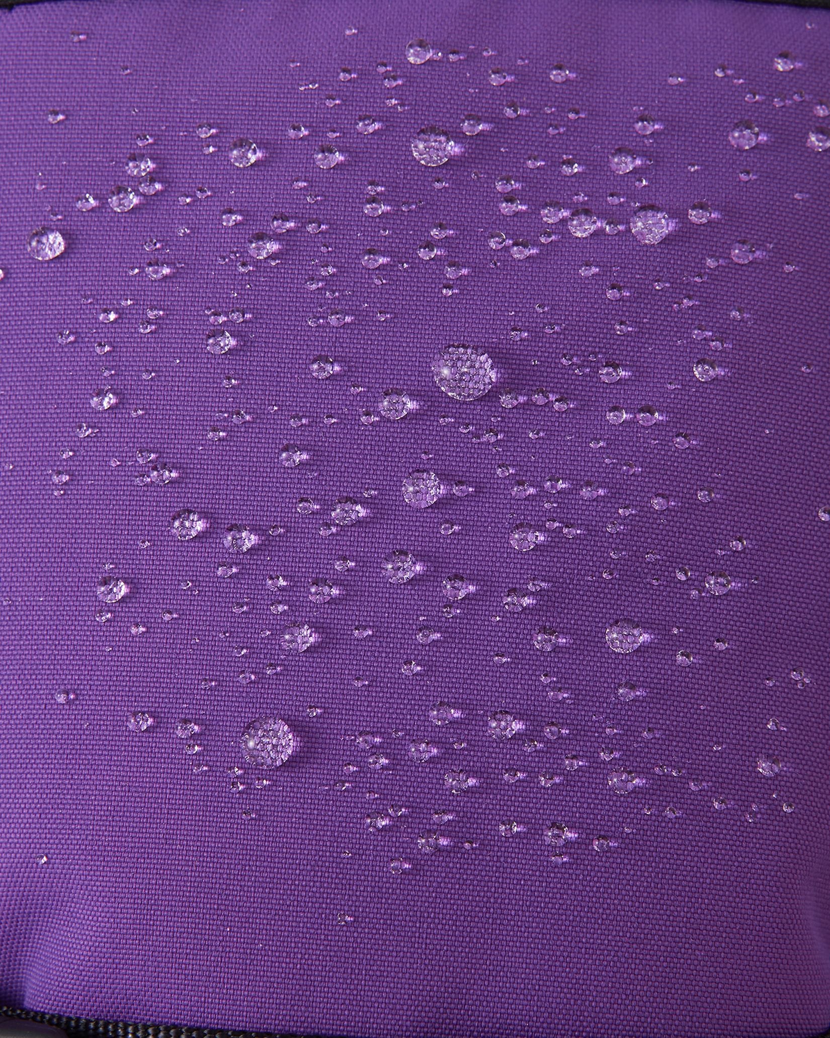 Macro close-up of water droplets actively beading and rolling off the plum purple outer shell of the Reima Skimba kids' ski gloves, demonstrating the highly effective waterproof and snow-repellent technology.