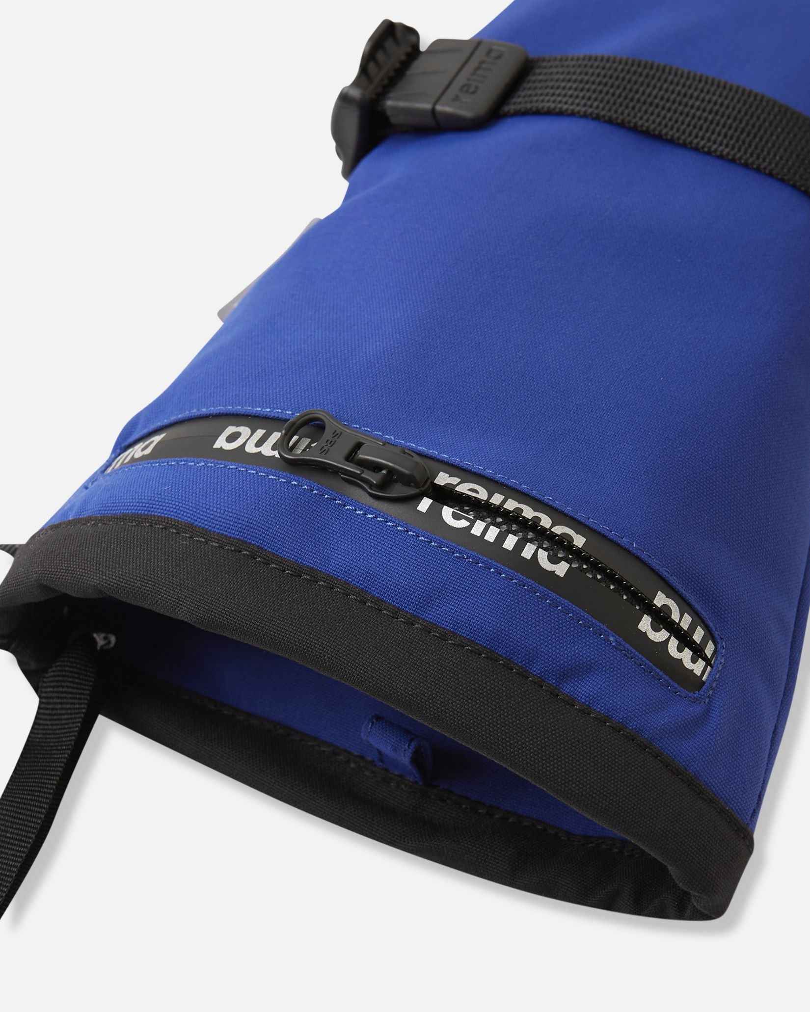Close-up detail of the extra-long cuff on the twilight blue Reima Skimba kids' ski gloves, highlighting the convenient water-resistant zippered ski pass pocket featuring the Reima logo.