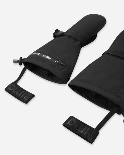 Close-up alternate view of the open gauntlet cuffs on the black Reima Snoukka children's snow mittens. The image highlights the adjustable wrist strap for a secure fit, a water-resistant zippered pocket, and the elastic safety wrist leashes essential for active winter sports.