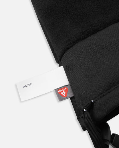 Detail of the inner cuff of the black Reima Snoukka kids' ski mittens, revealing the soft thermal fleece lining, a blank name tag, and the premium PrimaLoft insulation label for high-performance thermal regulation.