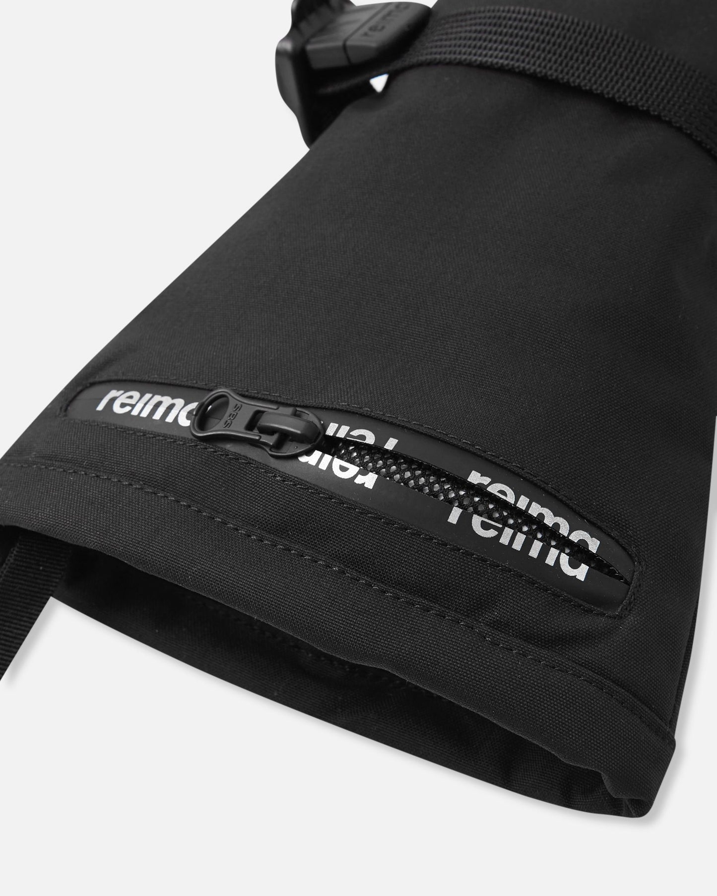 Close-up detail of the extra-long cuff on the black Reima Snoukka kids' ski mittens, highlighting the convenient water-resistant zippered ski pass pocket featuring the Reima logo.