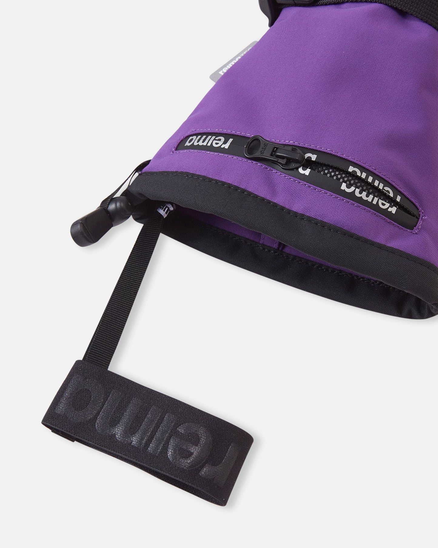 Close-up detail of the extra-long snow-blocking cuff on the plum purple Reima Snoukka kids' ski mittens, highlighting the convenient water-resistant zippered ski pass pocket and the attached elastic wrist leash.