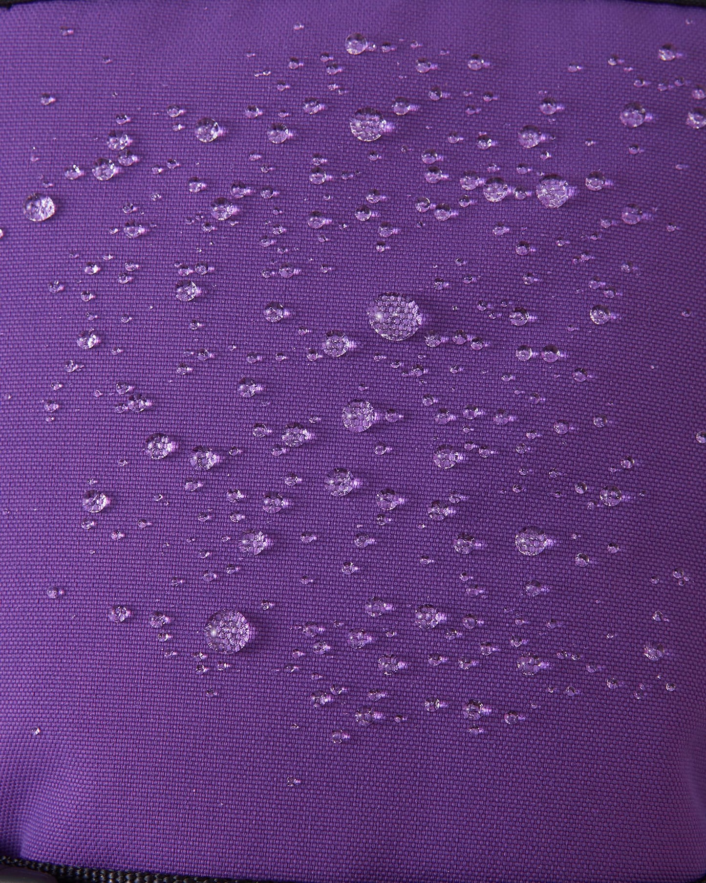 Macro close-up of water droplets actively beading and rolling off the plum purple outer shell of the Reima Snoukka kids' ski mittens, demonstrating the highly effective waterproof and snow-repellent technology.