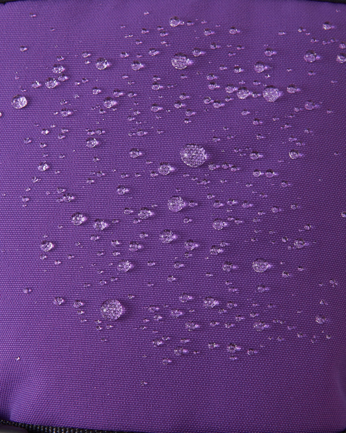 Macro close-up of water droplets actively beading and rolling off the plum purple outer shell of the Reima Snoukka kids' ski mittens, demonstrating the highly effective waterproof and snow-repellent technology.