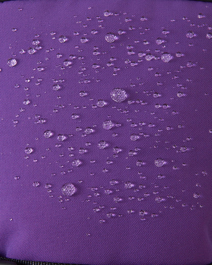 Macro close-up of water droplets actively beading and rolling off the plum purple outer shell of the Reima Snoukka kids' ski mittens, demonstrating the highly effective waterproof and snow-repellent technology.