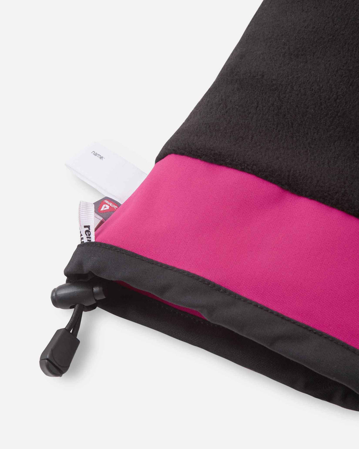 Detail of the inner cuff of the rosy berry pink Reima Snoukka kids' ski mittens, showing the soft black thermal fleece lining, a built-in customizable name tag, and the premium PrimaLoft insulation label indicating high-performance winter warmth.