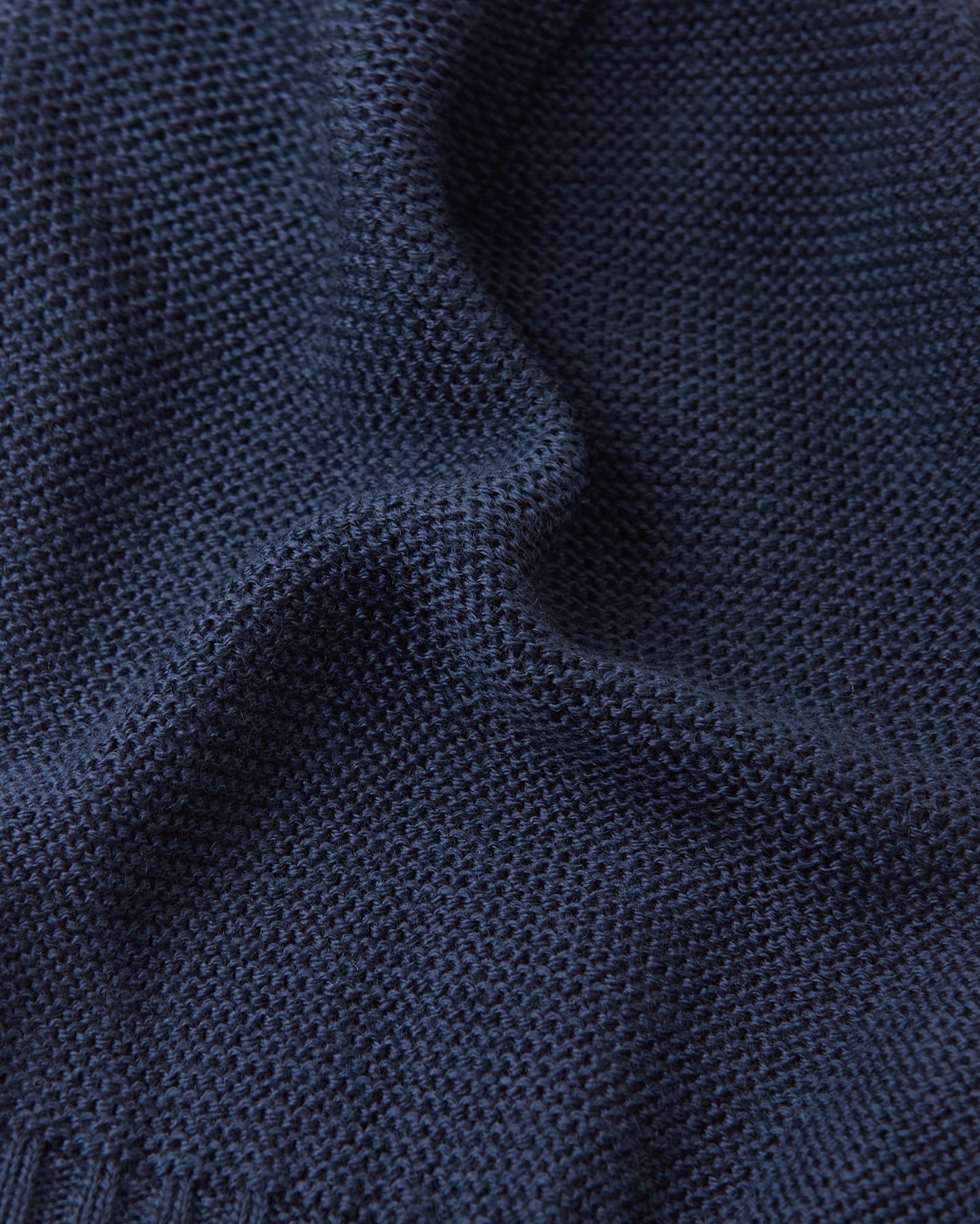 Macro photograph of the navy Reima Starrie kids' balaclava material, displaying the tightly woven, temperature-regulating merino wool knit that naturally wicks moisture.