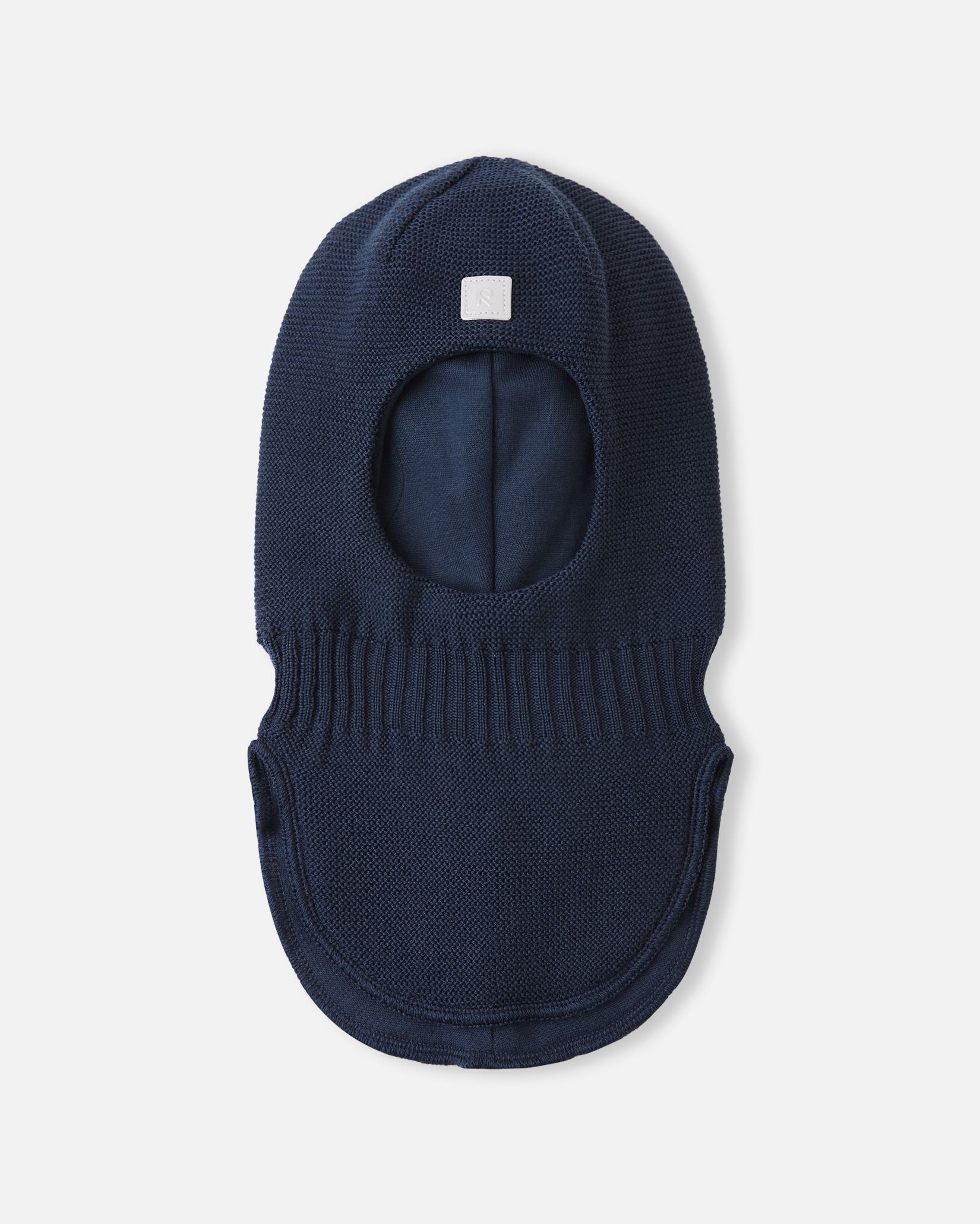 Top-down flat lay of the navy Reima Starrie youth windproof balaclava, featuring the front reflective square logo and ribbed neck gather for a secure fit under snow gear.
