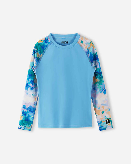 Front view of the Reima Sukeltaja kids' UPF 50+ sunproof rash guard, featuring a solid fresh blue body and a stylish watercolor floral print on the long raglan sleeves for maximum UV protection.