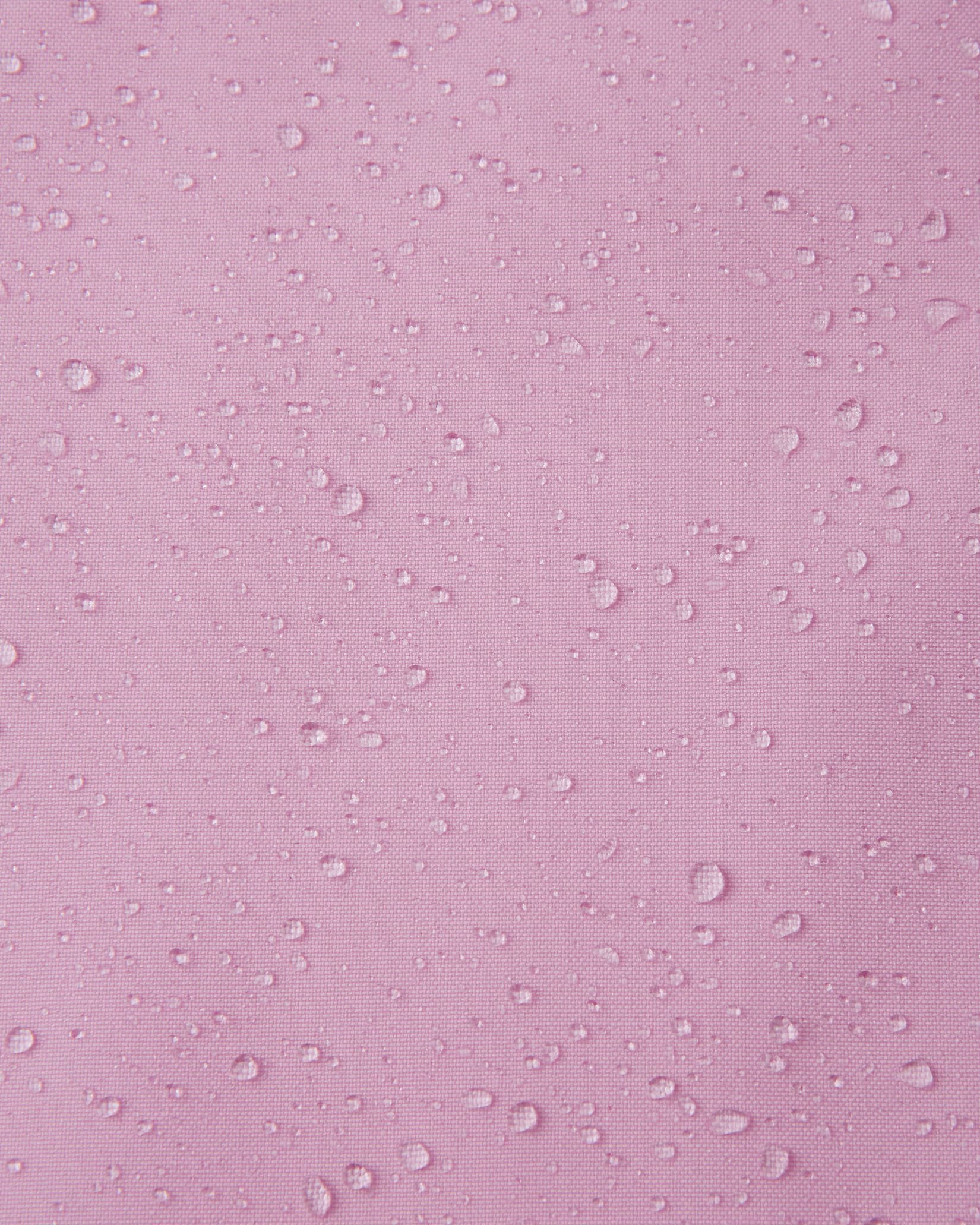Macro close-up of water droplets tightly beading on the light heather pink Reimatec fabric of the Sulkava girls' fall jacket, demonstrating its advanced waterproof and rain-resistant capabilities for wet weather.