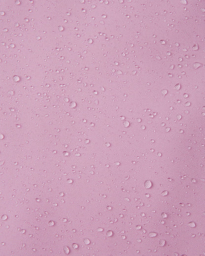 Macro close-up of water droplets tightly beading on the light heather pink Reimatec fabric of the Sulkava girls' fall jacket, demonstrating its advanced waterproof and rain-resistant capabilities for wet weather.