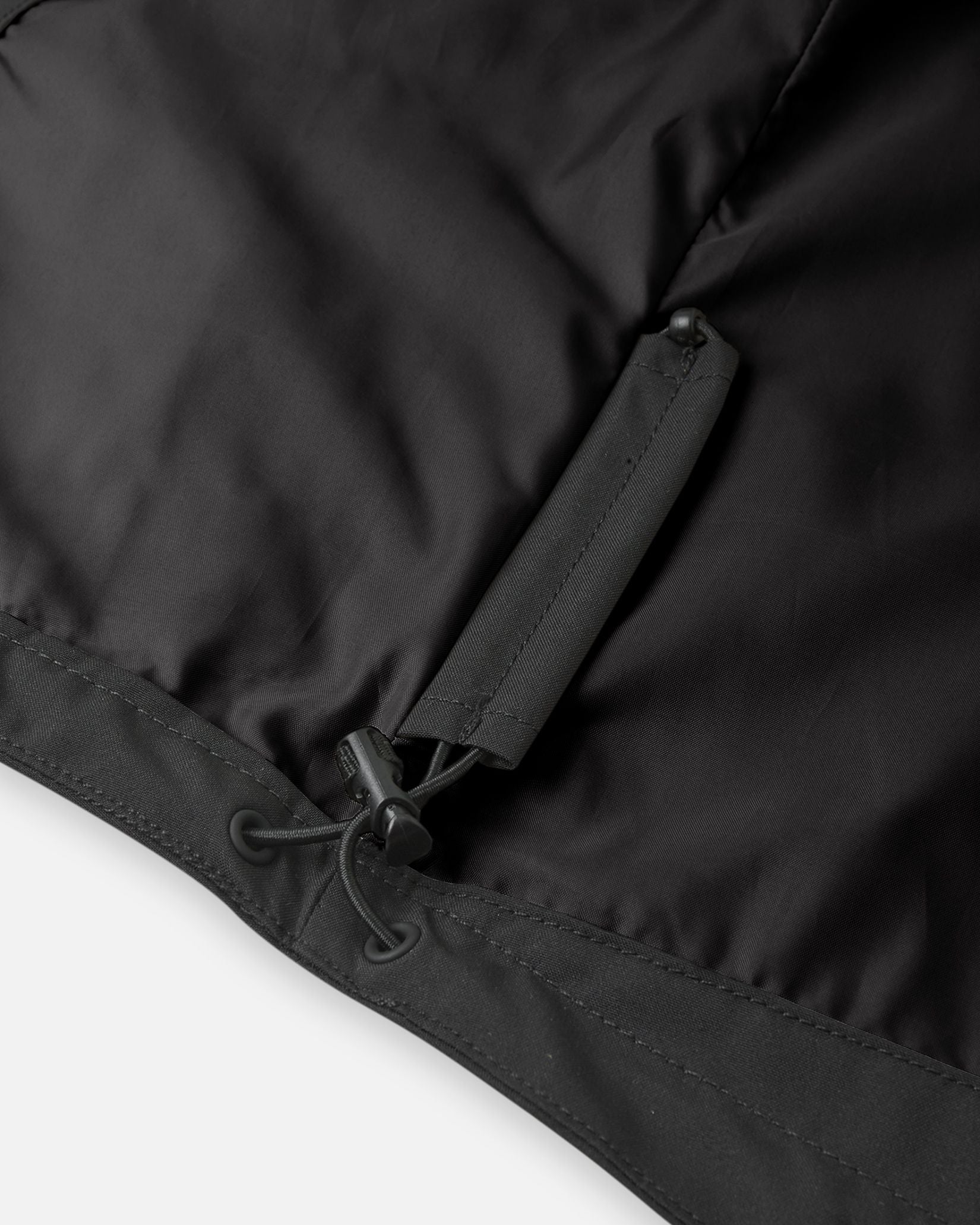 Close-up of the interior lower hem on the Reima Sulkava kids' jacket, showcasing the concealed, adjustable bungee cord and toggle system designed to cinch the waist and block out cold wind.