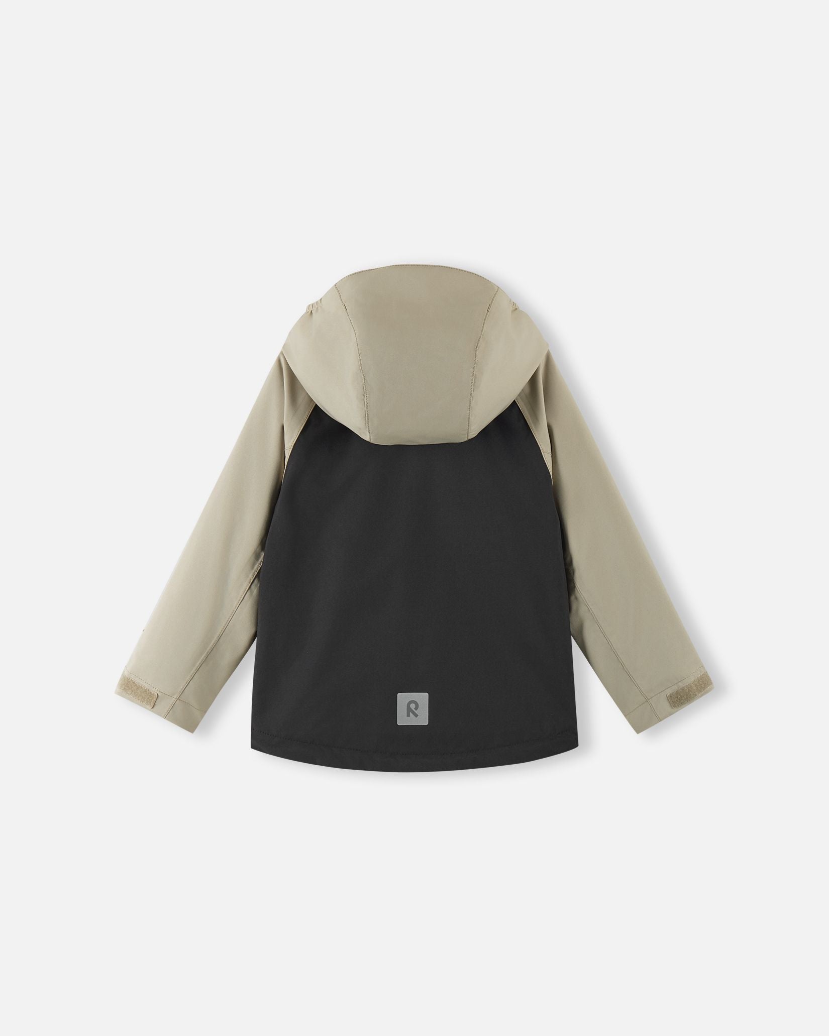 Back view of the Reima Sulkava kids' fall jacket in black and beige, showing the attached hood and a square reflective safety patch positioned near the lower hem for visibility in low light.