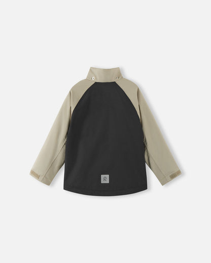 Back view of the color-block black and beige Reima Sulkava kids' fall jacket with the detachable hood removed, revealing a high stand collar that protects the neck from chilly autumn winds.