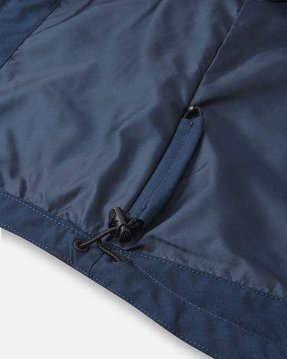 Interior detail shot of the lower hem on the navy blue Reima Sulkava kids' jacket, showcasing the concealed adjustable bungee cord and toggle system used to cinch the hem for a windproof fit.