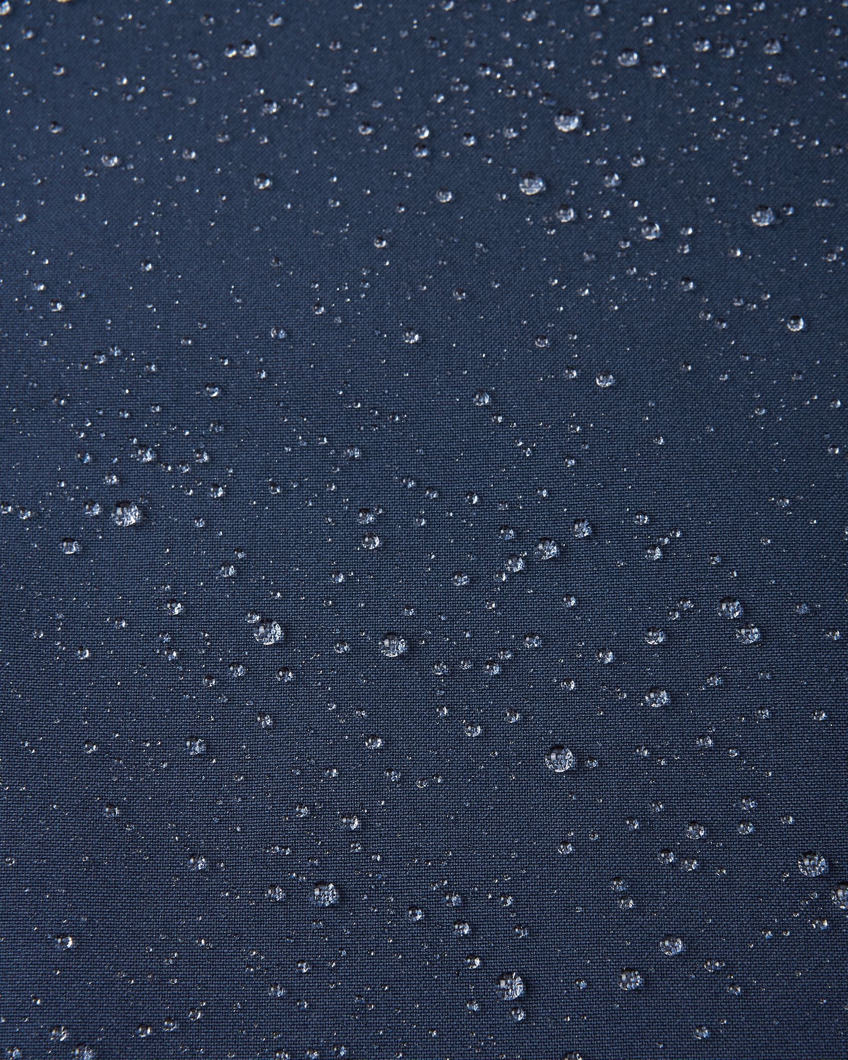 Macro close-up showing water droplets tightly beading on the navy blue Reimatec fabric of the Sulkava kids' fall jacket, demonstrating its advanced waterproof and weather-resistant performance in wet conditions.