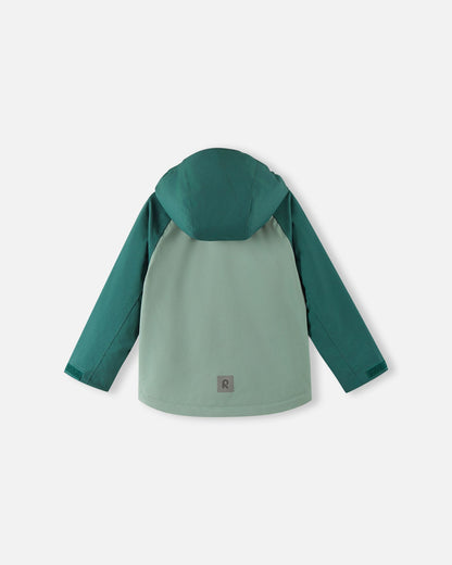Back view of the Reima Sulkava kids' fall jacket in light and dark stone green, showing the attached hood and a square reflective safety patch positioned near the lower hem for excellent visibility in low light conditions.