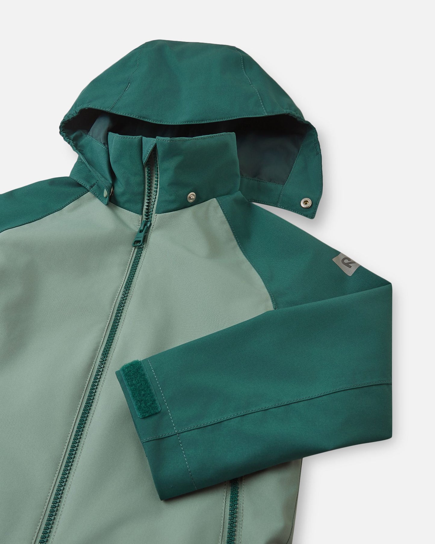 Close-up of the child-safe detachable hood on the Reima Sulkava fall jacket in stone green, illustrating the durable snap buttons that easily release if the hood gets caught while a child is playing outdoors.