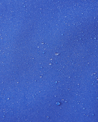 Close-up of water droplets beading on the sparkly blue fabric of the Reima Suojala kids jacket, demonstrating its waterproof capabilities.