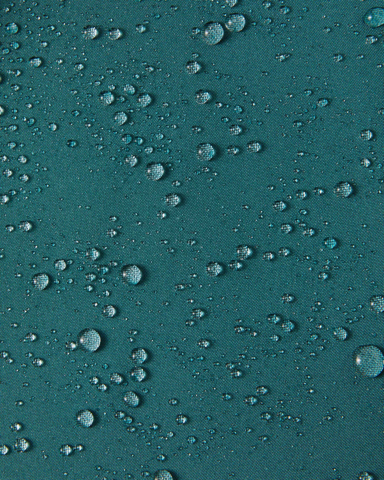 Close-up of water droplets beading on the dark teal Reimatec fabric of the Syddi kids' jacket, demonstrating its waterproof and weather-resistant properties.