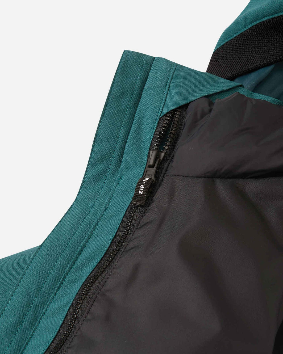 Close-up detail of the internal zip-in system on the Reima Syddi jacket, showing how the black quilted inner jacket easily attaches to the dark teal outer shell.