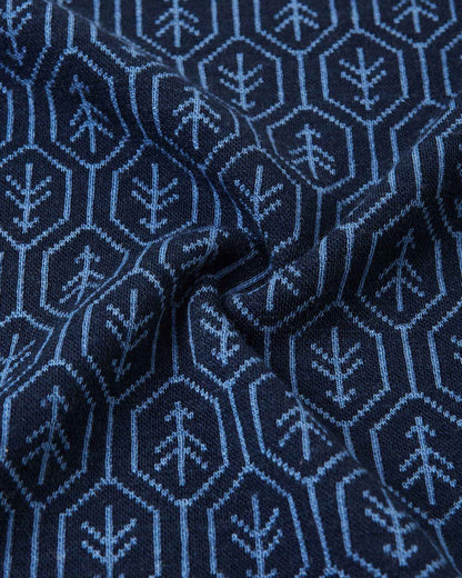 Macro close-up of the ultra-soft navy blue merino wool fabric from the Reima Taival kids' base layer, highlighting the fine natural knit texture and intricate hexagonal forest tree pattern designed to trap body heat naturally.