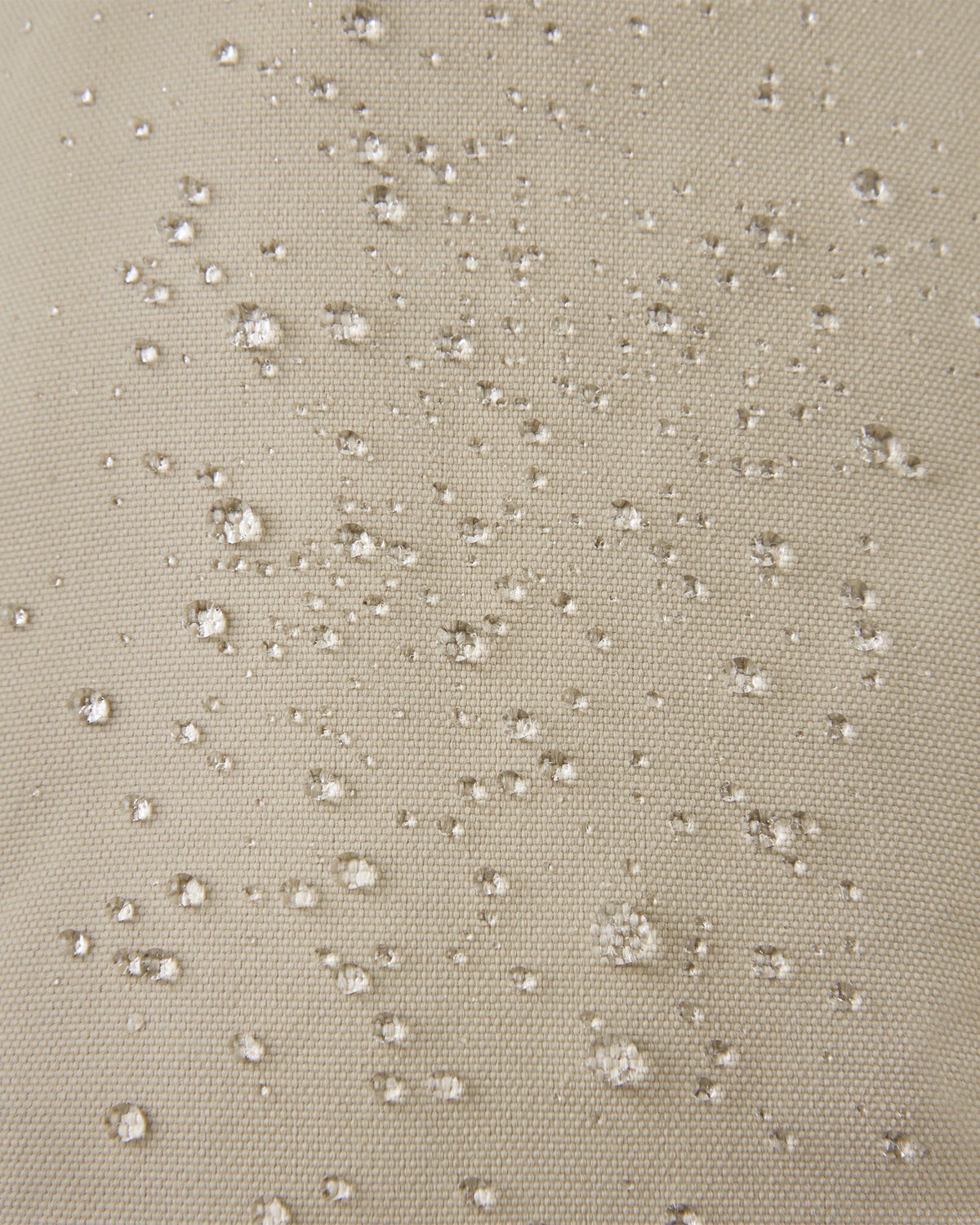 Macro close-up of water droplets actively beading off the earthy beige outer shell of the Reima Tartu kids' winter gloves, highlighting the highly effective waterproof, breathable membrane.