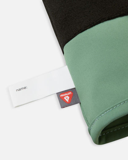 Detail of the inner cuff of the green clay Reima Tartu kids' winter gloves, revealing the soft black thermal fleece lining, a blank customizable name tag, and the premium PrimaLoft insulation label.