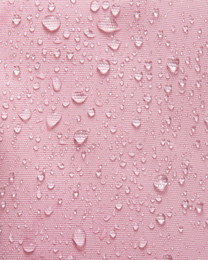 Close-up shot demonstrating the water and dirt repellent technology on the grey pink Reima Tassuin toddler mittens, with multiple water droplets beading on the woven fabric surface.