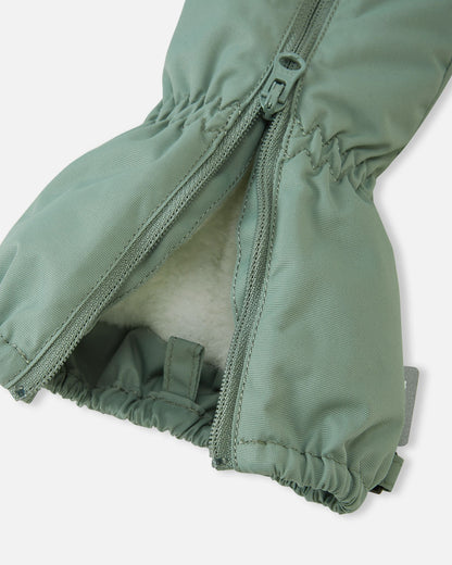 Close-up of the stone green Reima Tassuin toddler mitten with the high-quality YKK top zipper open, revealing a plush, warm 41% wool and 59% polyester blend insulation lining that protects children's hands in freezing temperatures.