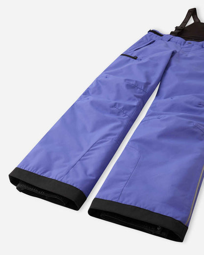 Detail view of the lower legs on the breezy violet Reima Terrie kids' ski pants, emphasizing the rugged reinforced hems to protect against ski edges and the inner elastic snow locks designed to securely grip winter boots.