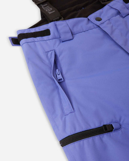 Close-up detail of the hip and thigh on the breezy violet Reima Terrie kids' ski pants, highlighting secure zippered pockets and adjustable hook-and-loop waist tabs for a custom, draft-free fit.