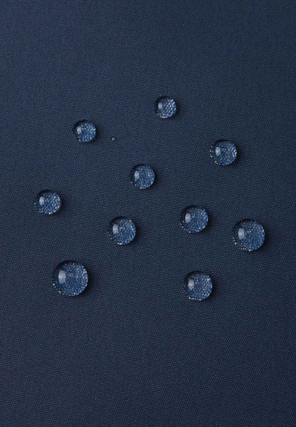 Macro close-up of water droplets actively beading and rolling off the navy blue outer shell of the Reima Terrie kids' ski pants, visually highlighting the high-performance breathable and waterproof Reimatec technology.